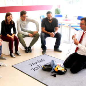 Herr Stephan Macht erklärt einer Gruppe den Defibrillator